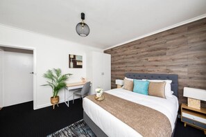 A modern hotel room with a bed, desk, and chair.
