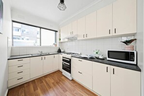 Una cocina moderna con armarios blancos, encimera negra, estufa y microondas.