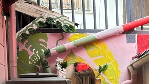 A compact room with a water tank, a small table, and a wall with a green and yellow mural.