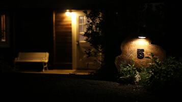 A dimly lit outdoor area with a bench and a wooden structure with a light.