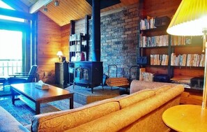 Una sala de estar acogedora con chimenea, paredes de madera y una estantería llena de libros.