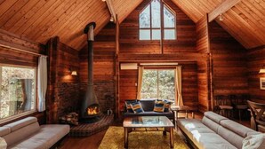 Ein rustikales Blockhaus-Interieur mit Kamin, Holzwänden und hoher Decke.