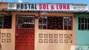 A building with a sign reading "HOSTAL SOL & LUNA" and contact information.