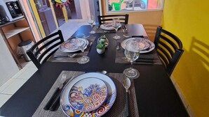 A dining area with a table set for four, chairs, and a window with a view of the street.