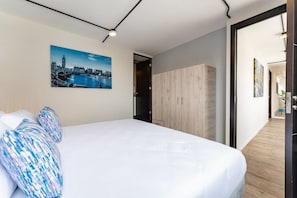 Una camera d'albergo con un grande letto, un quadro che raffigura un panorama cittadino e un armadio in legno.