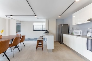 Una cucina moderna con mobili bianchi, un frigorifero in acciaio inossidabile, un forno a microonde e una macchina da caffè.