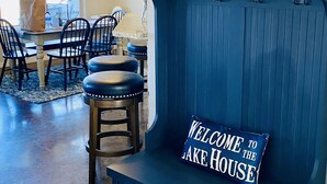 A dining area with a blue bar seating, a sign reading "Welcome to the Lake House," and a sailboat decoration on the wall. - Cozy and Relaxing Lake House close to Lake of the Arbuckles (Sulphur)