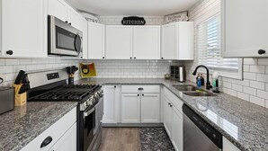 A modern kitchen with white cabinets, a built-in microwave, a gas stove, and a dishwasher. - Pet-Friendly | Large Group | Hot Tub - All Year (Bay City)