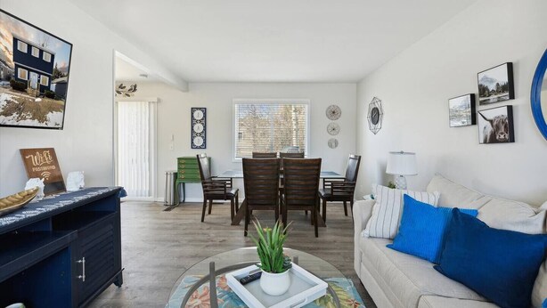 A modern living room with a dining area, a sofa with blue cushions, and a coffee table with a plant. - Pet-Friendly | Large Group | Hot Tub - All Year (Bay City)