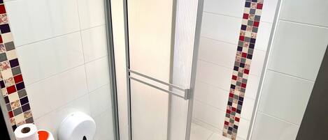 A bathroom with a shower, toilet, and hand dryer.
