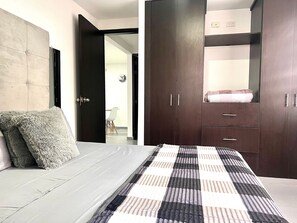 Une chambre à coucher comprenant un lit, une armoire et une porte donnant sur une autre pièce.