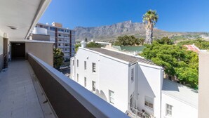 A balcony with a view of a mountain and a palm tree. - Bright and Homey 1 Bedroom in Gardens (Cape Town)