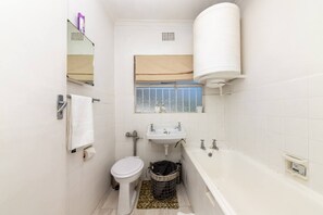 A compact bathroom with a toilet, sink, and bathtub.