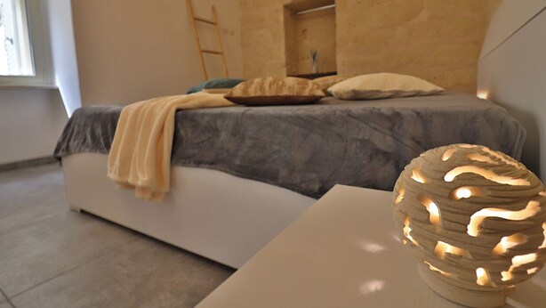 Une chambre à coucher avec un lit, des oreillers, une table de chevet et une lampe décorative.