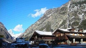 A mountain lodge with wooden cabins, a sign for a restaurant, and a view of snow-covered mountains. - Apartment La Gran Becca - ID 528 (Antey-Saint-Andre)