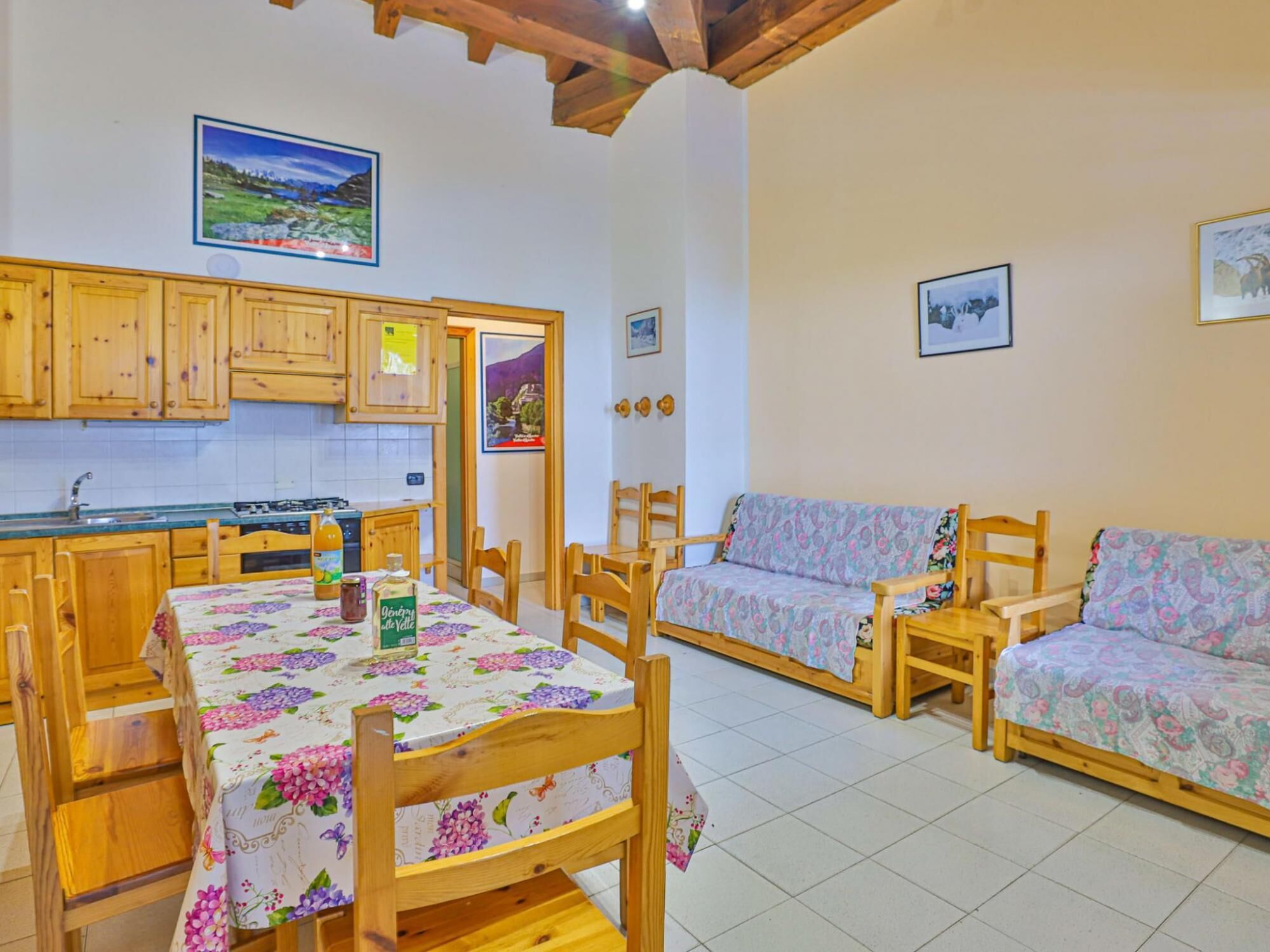 Un espacio de sala acogedor con muebles de madera, una mesa de comedor con mantel floral y una cocina con armarios de madera.