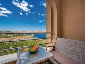 A balcony with a table, a bowl of fruit, and a glass of orange juice. - Apartments Villa Kim (Stinica)