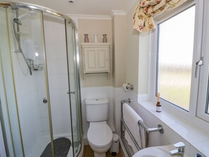 A bathroom with a glass-enclosed shower, a toilet, and a sink with a window above. - Fairview House (Kidderminster)