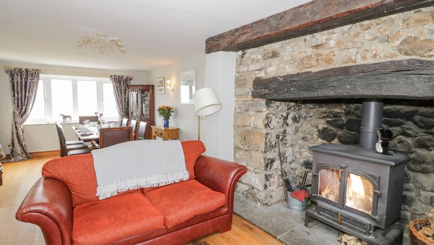 A cozy living room with a stone fireplace, a leather sofa, and a dining area with a wooden table and chairs.