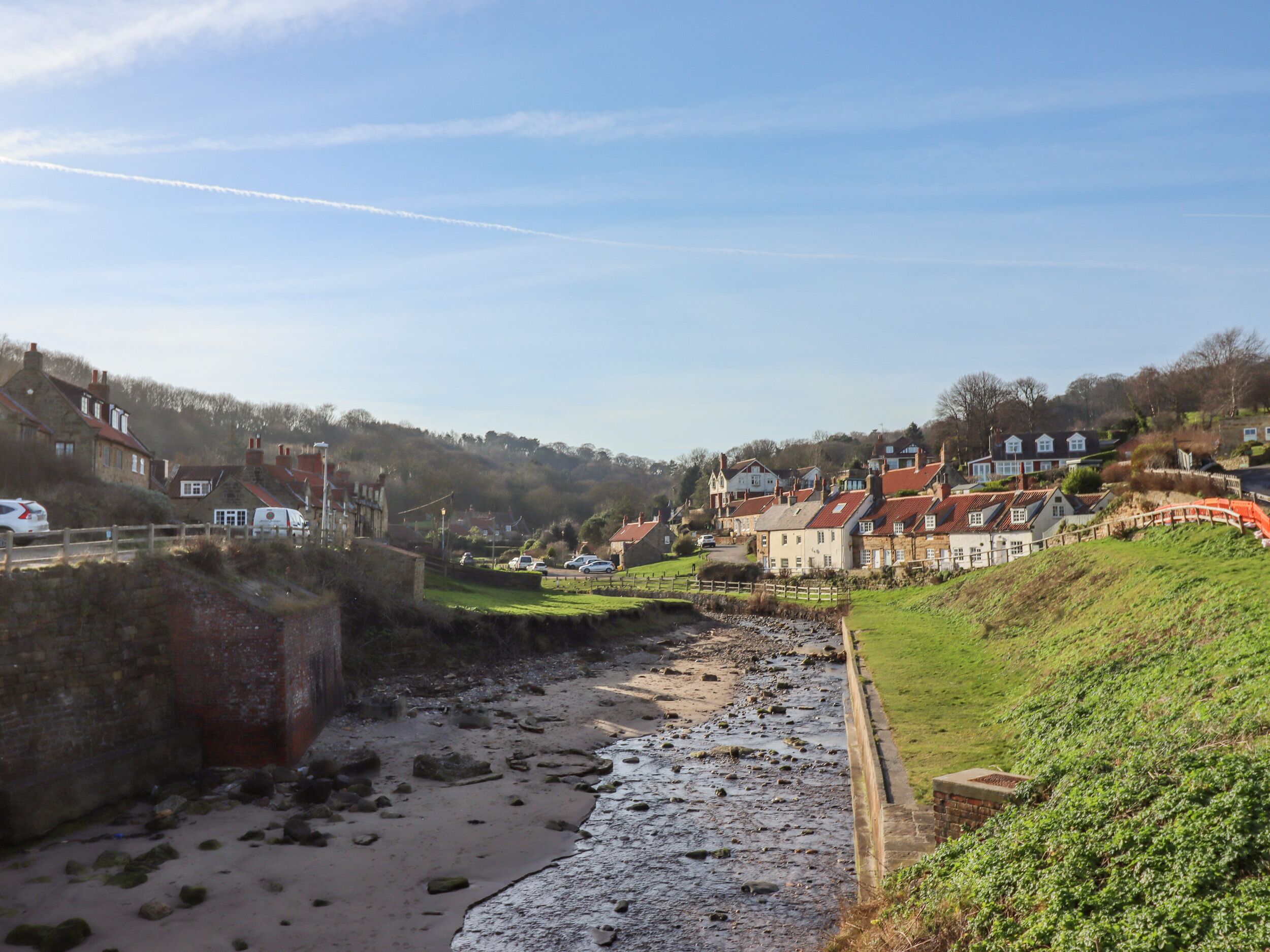 A coastal town with stone buildings, a sandy beach, and a rocky shoreline.