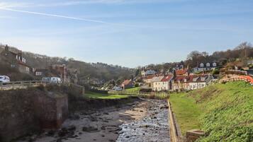 A coastal town with stone buildings, a sandy beach, and a rocky shoreline.