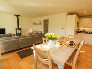 Una sala moderna con sofá, mesa de comedor y cocina al fondo.