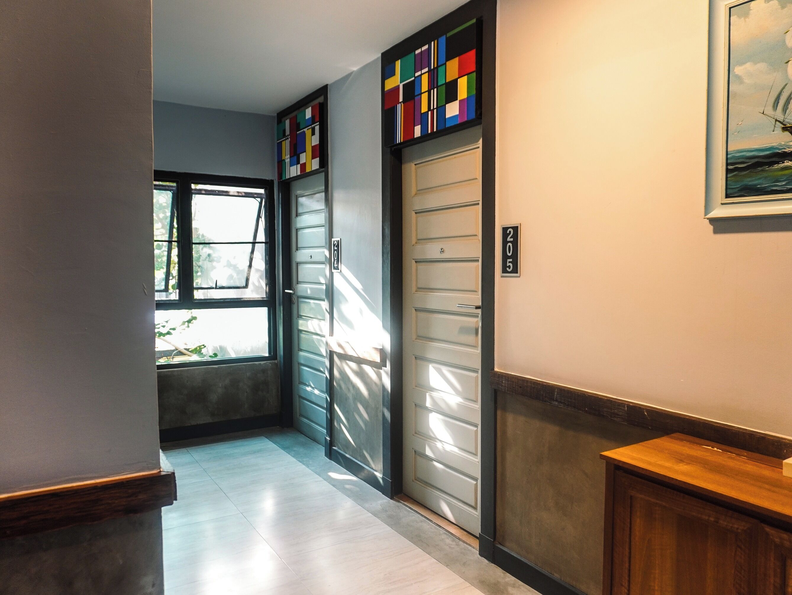 A hallway with a door marked 205, a window with blinds, and a door with a colorful geometric pattern.