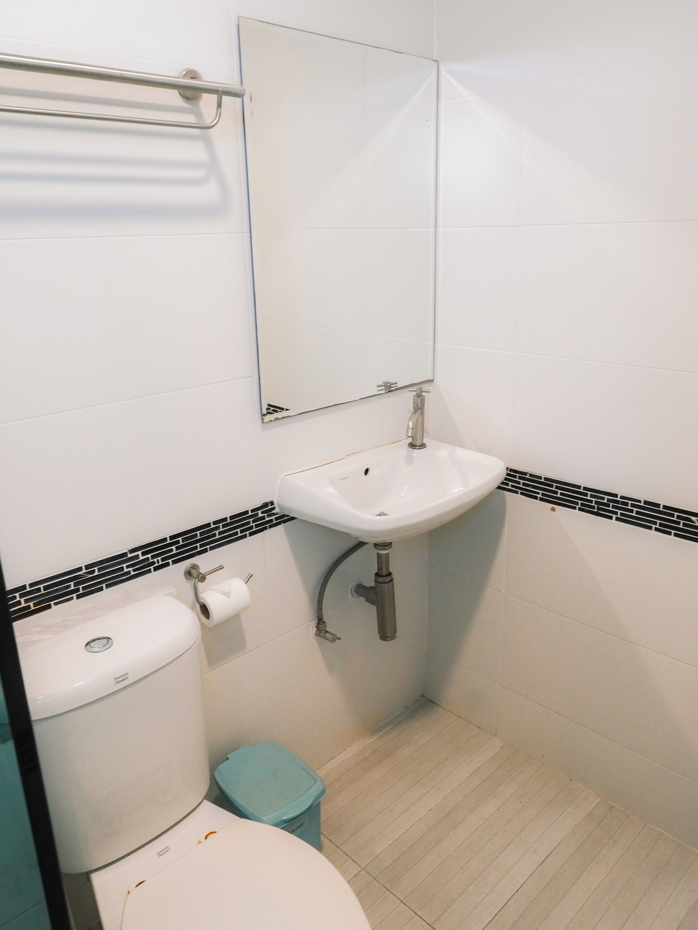 A bathroom with a toilet, sink, and mirror.