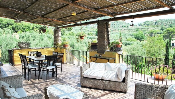 An outdoor patio with a table and chairs, a wicker sofa, and a view of a lush green landscape. - Holiday Home Chevalier With Terrace and Swimming Pool (Itri)