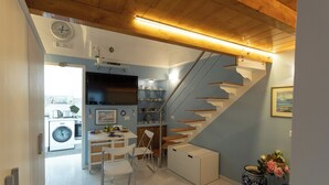 A modern kitchen with a built-in oven, a dining area with a white table and chairs, and a staircase with wooden steps. - Freeholiday House in Amalfi Coast (Minori)