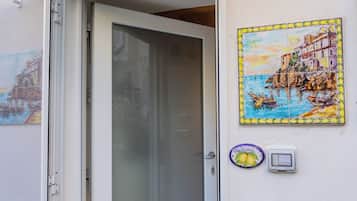 Una puerta con un panel de vidrio esmerilado, un letrero de bienvenida con diseño de limón y un cuadro de una escena costera colorida en la pared.