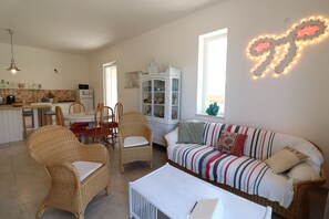 A living room with wicker furniture, a striped sofa, a white coffee table, and a cabinet with glass doors.