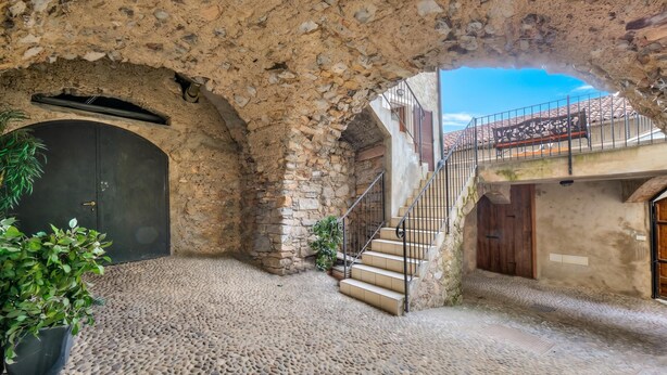 Un patio interior con paredes de piedra, una escalera y una planta en maceta.