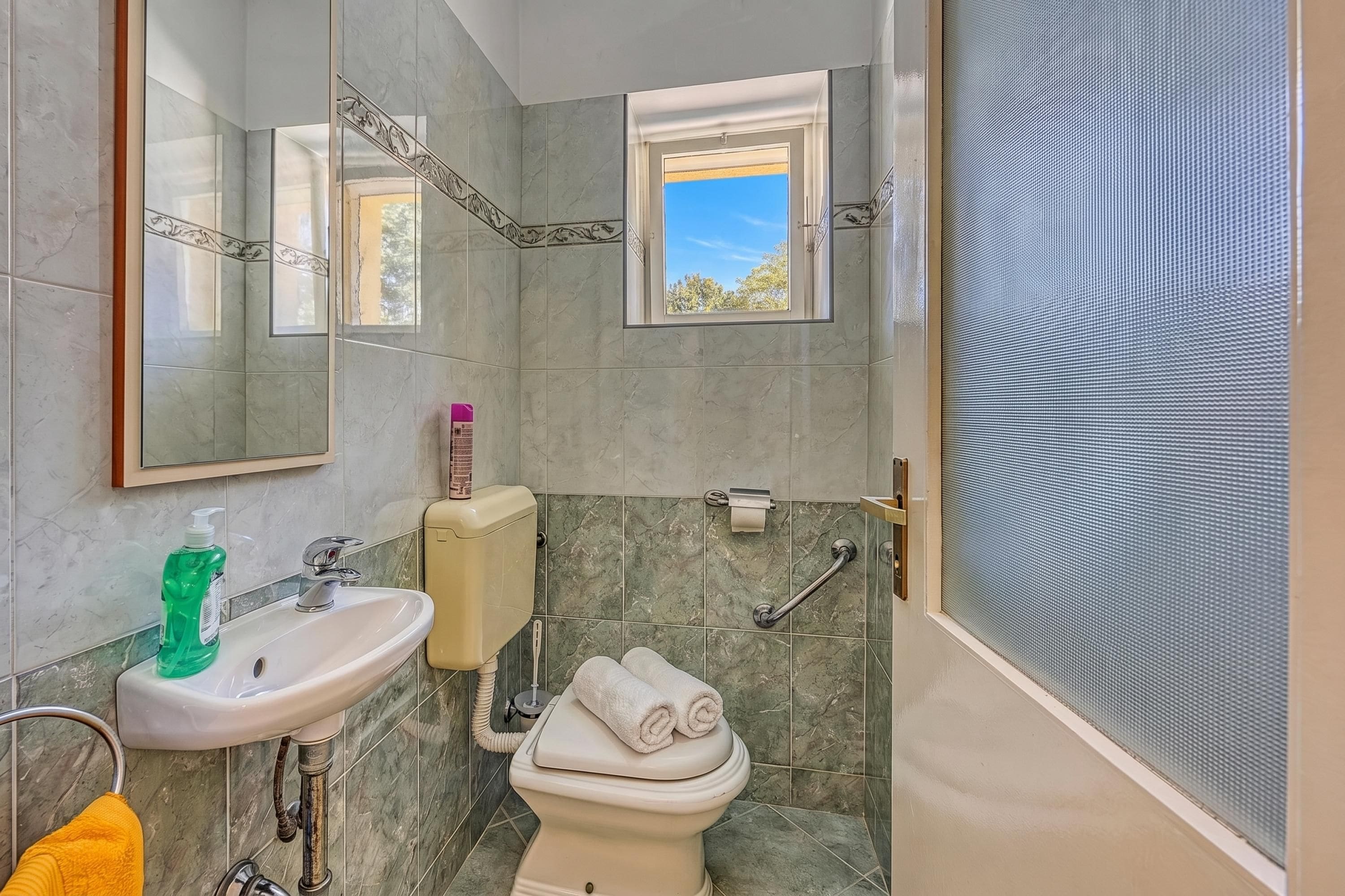 A bathroom with a sink, toilet, and window.