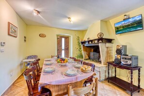 A dining area with a round table set for four, surrounded by wooden chairs. - Pool House Klarina (Pican)