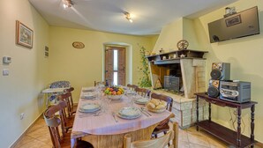 Un coin repas avec une table ronde dressée pour six personnes, entourée de chaises en bois.