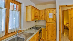 A kitchen with wooden cabinets, a stainless steel sink, and a gas stove. - Apartment La Gran Becca - ID 523 (Antey-Saint-Andre)