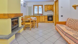 A compact kitchen with wooden cabinets, a dining table with chairs, a built-in oven, and a fireplace. - Apartment La Gran Becca - ID 523 (Antey-Saint-Andre)