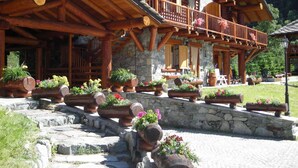A wooden chalet with a stone facade, wooden balconies, and outdoor seating areas. - Apartment La Gran Becca - ID 3949 (Antey-Saint-Andre)