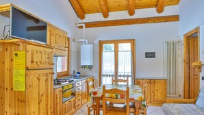 A cozy kitchen with wooden cabinets, a stove, and a dining table with chairs. - Apartment La Gran Becca - ID 3949 (Antey-Saint-Andre)