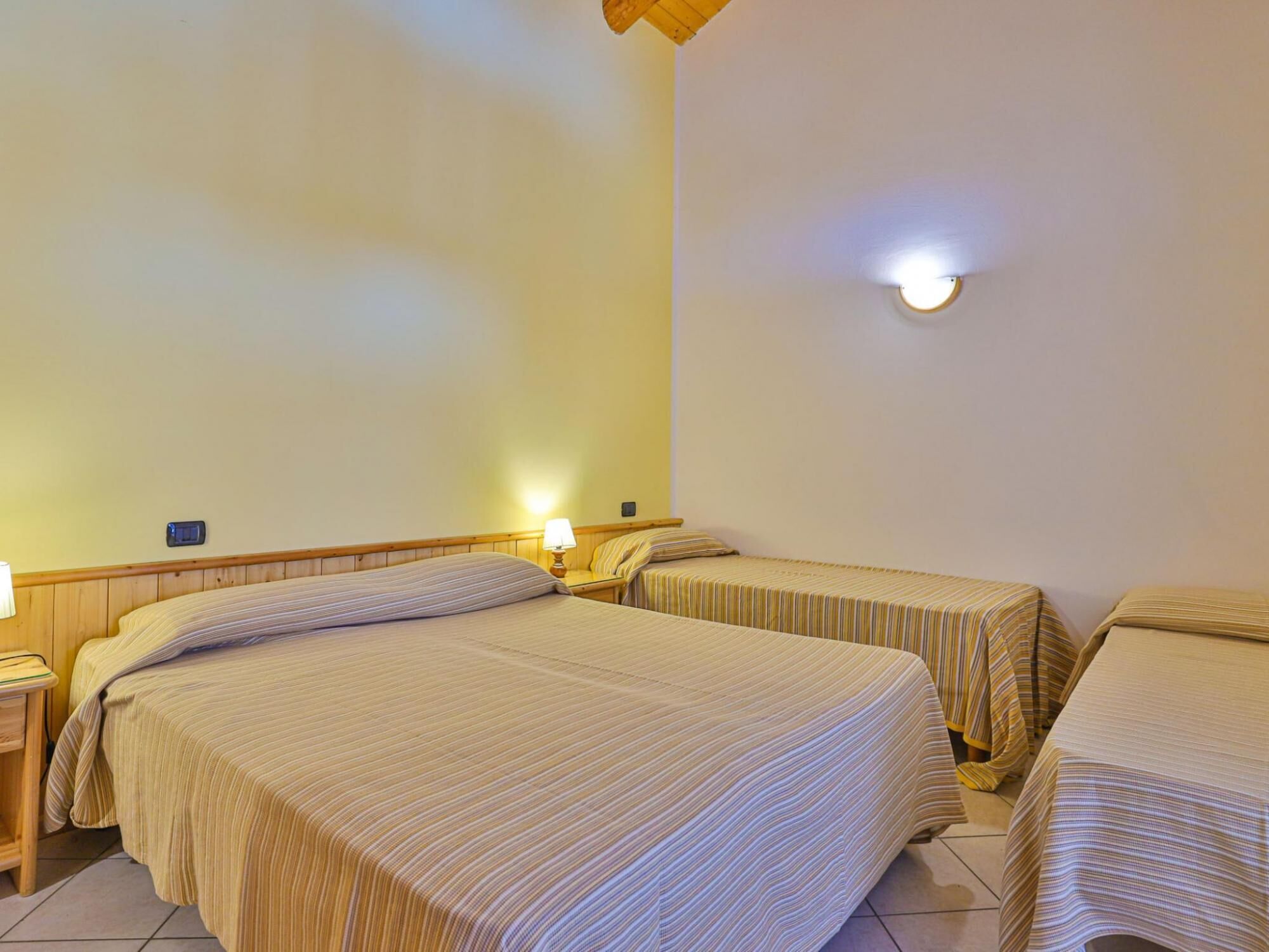 Ein Hotelzimmer mit zwei Einzelbetten, einem Nachttisch mit Lampe und einer Wandleuchte.