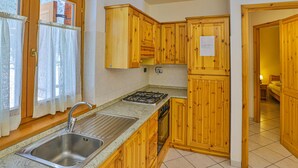 Una cocina con armarios de madera, un lavamanos de acero inoxidable y una estufa a gas.