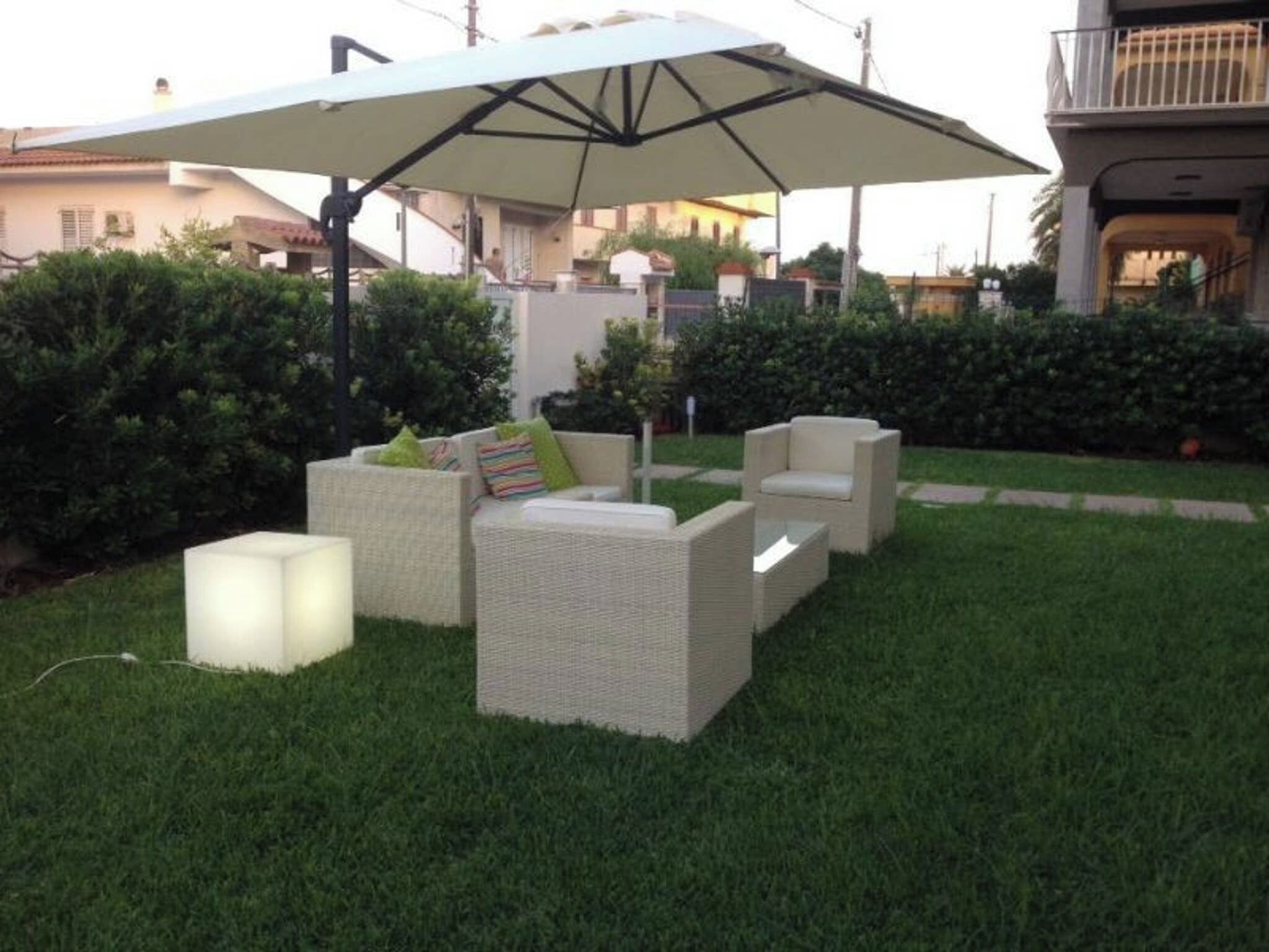 Un'area salotto all'aperto con mobili in vimini e un ombrellone grande.