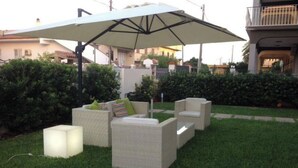 Un área de estar al aire libre con mobiliario de mimbre y un paraguas grande.