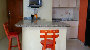 A kitchen with a granite countertop, a microwave, a blender, and two red chairs. - Apartment in Cartagena Ocean Front Num1c5 (Cartagena)