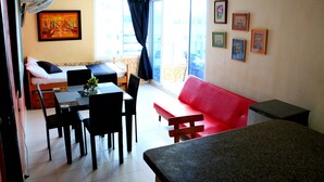 A room with a dining table, chairs, a red sofa, a small kitchen area, and a balcony with a view. - Apartment in Cartagena Ocean Front Num1c5 (Cartagena)