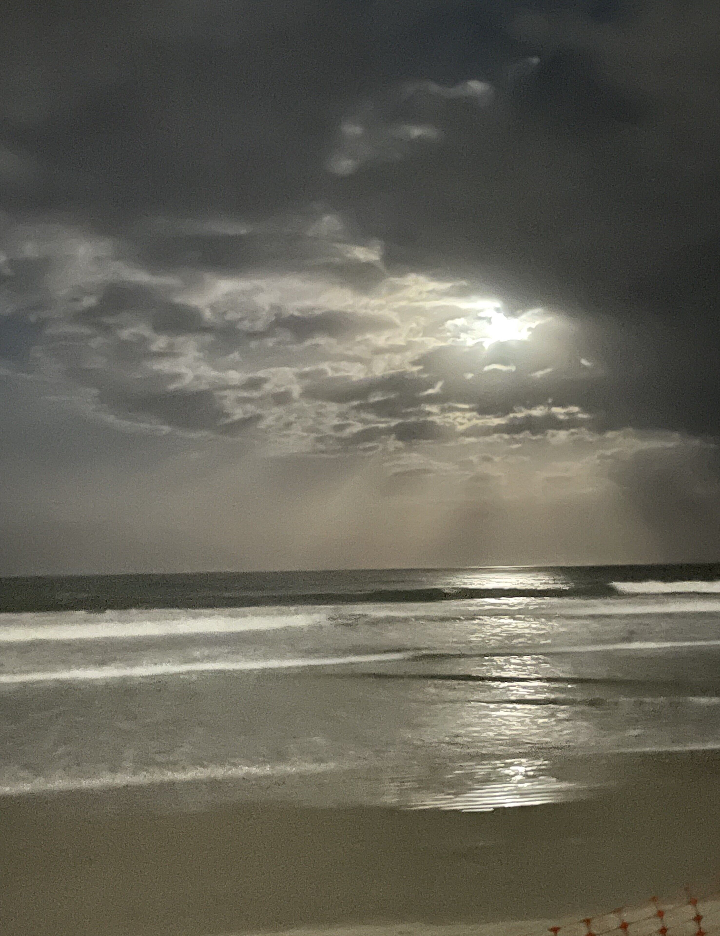A beach with waves and a cloudy sky.