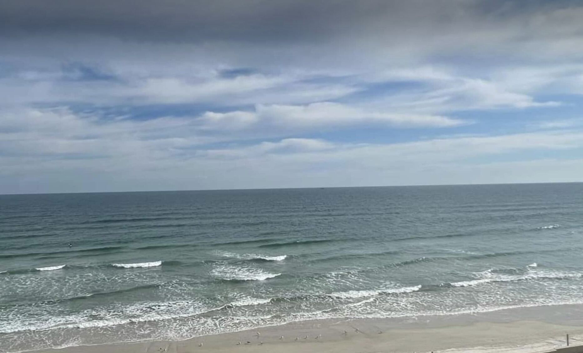 A beach with waves and a cloudy sky.