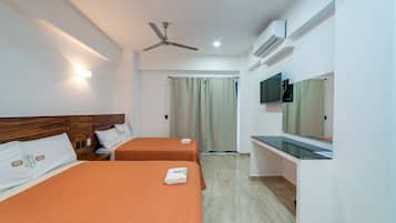 Une chambre d’hôtel avec deux lits, un ventilateur de plafond, un appareil de climatisation, une télévision et un bureau.