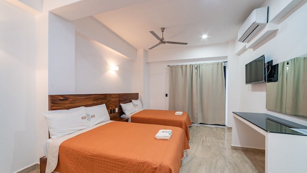 A hotel room with two beds, a ceiling fan, an air conditioning unit, a TV, and a sliding door leading to a balcony.